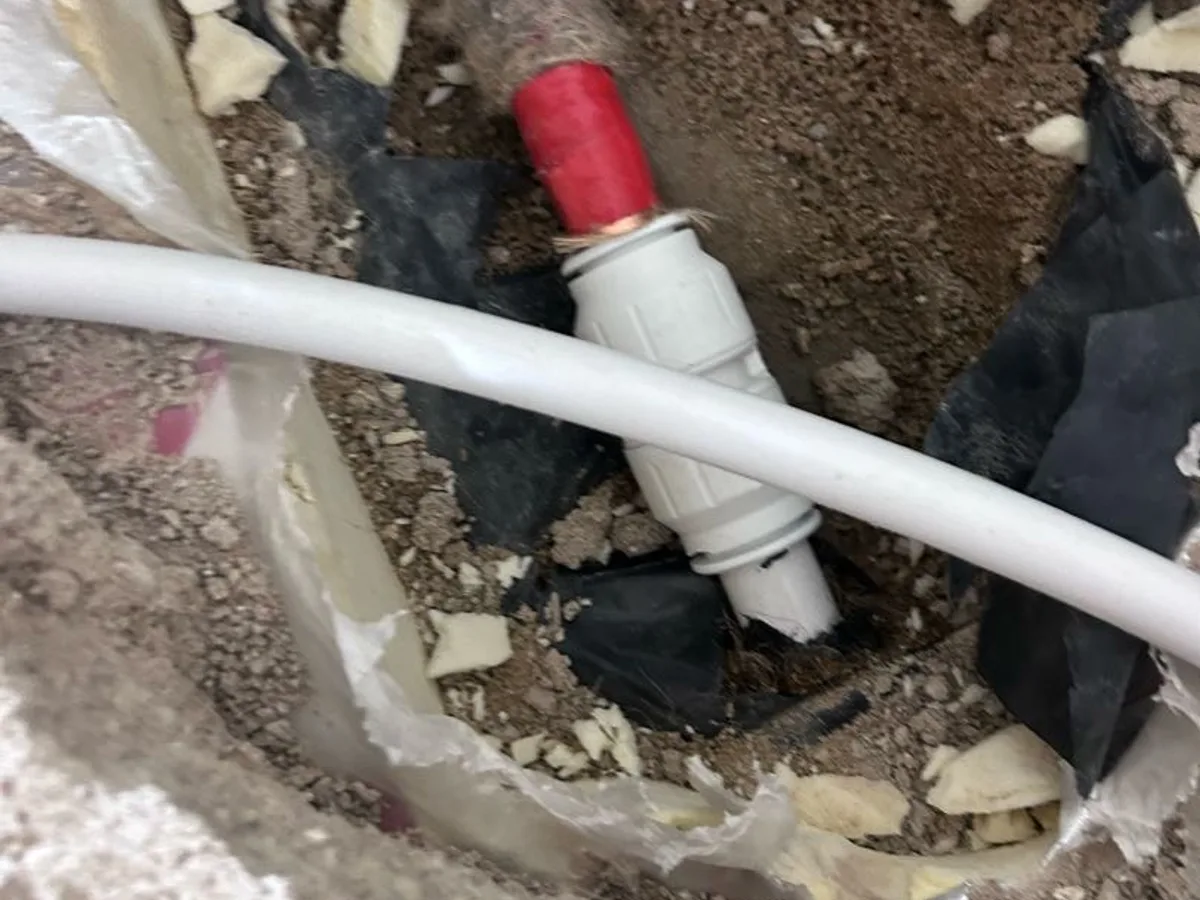 push-fit coupling installed on 22mm PEX pipe in excavated floor as repair completed