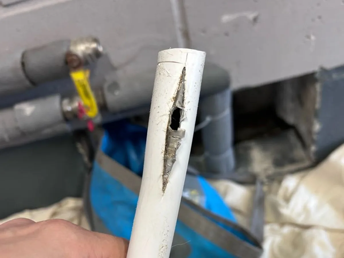 fault identified at large split in 22mm PEX underfloor heating pipe held in hand — leak located at