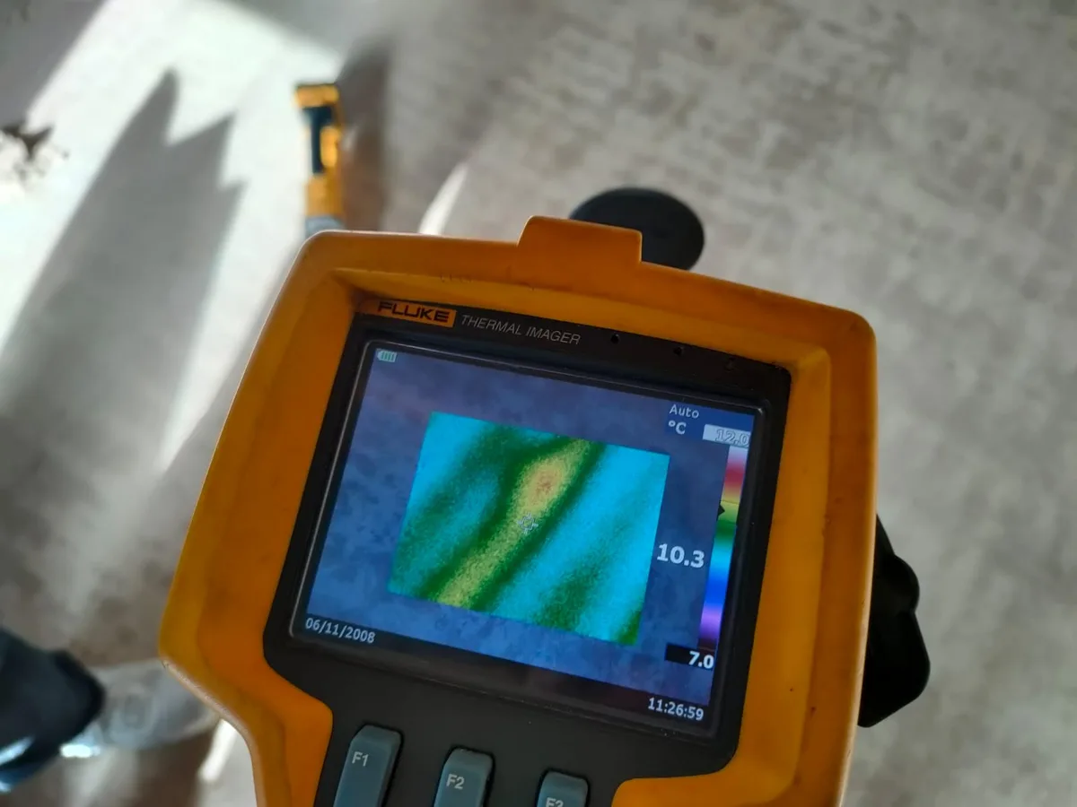 thermal imaging camera screen showing faint warm anomaly in concrete floor during leak detection
