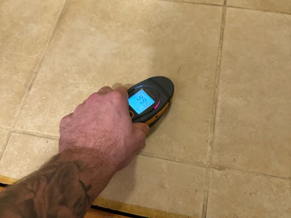 damp meter reading on ceramic bathroom floor tiles during leak detection