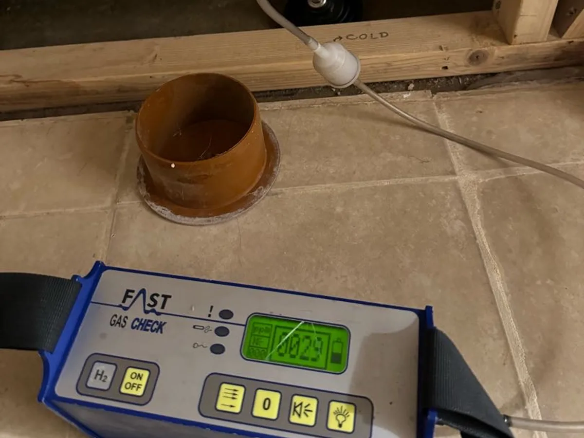 tracer gas detector picking up readings behind bathroom boxing during leak detection