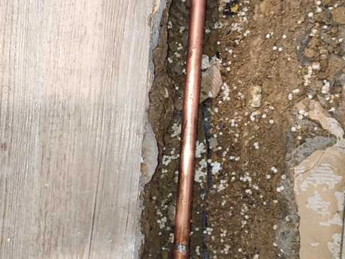 new short section of 15mm copper pipe installed in screed trench as repair completed