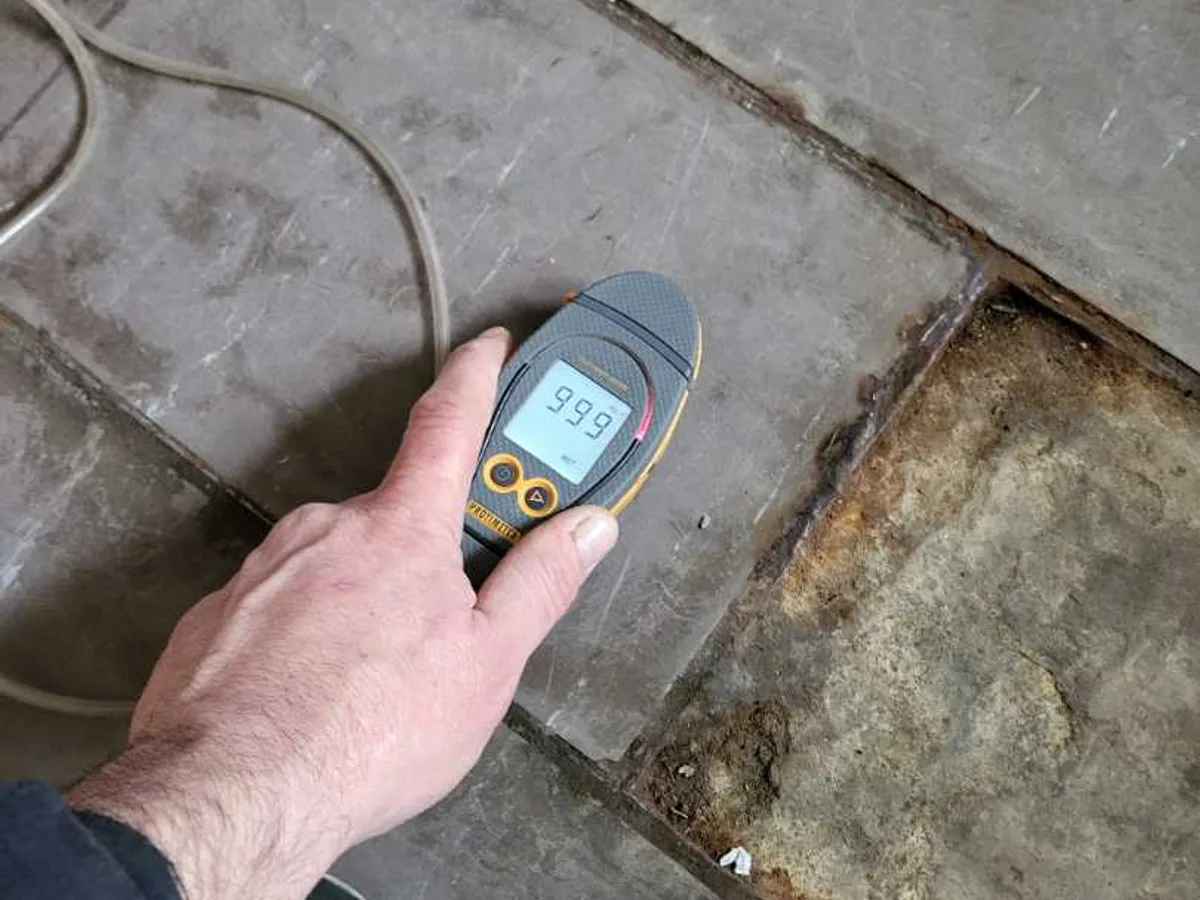leak located at classroom concrete floor showing moisture meter reading of 99.9