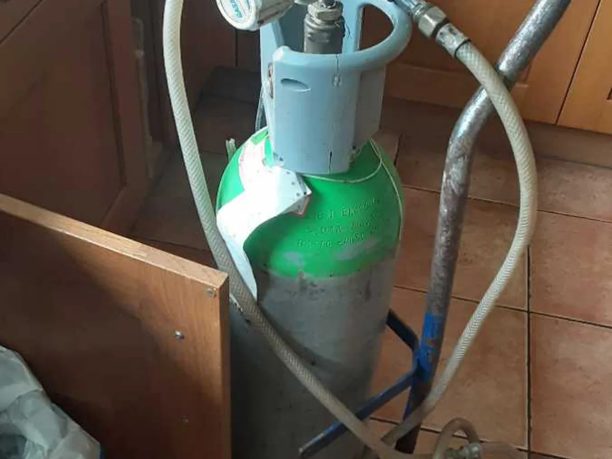 tracer gas cylinder with regulator connected to underground pipework during leak detection