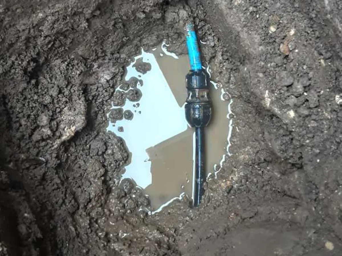 leak located at transition joint on black poly underground mains pipe exposed beneath pathway