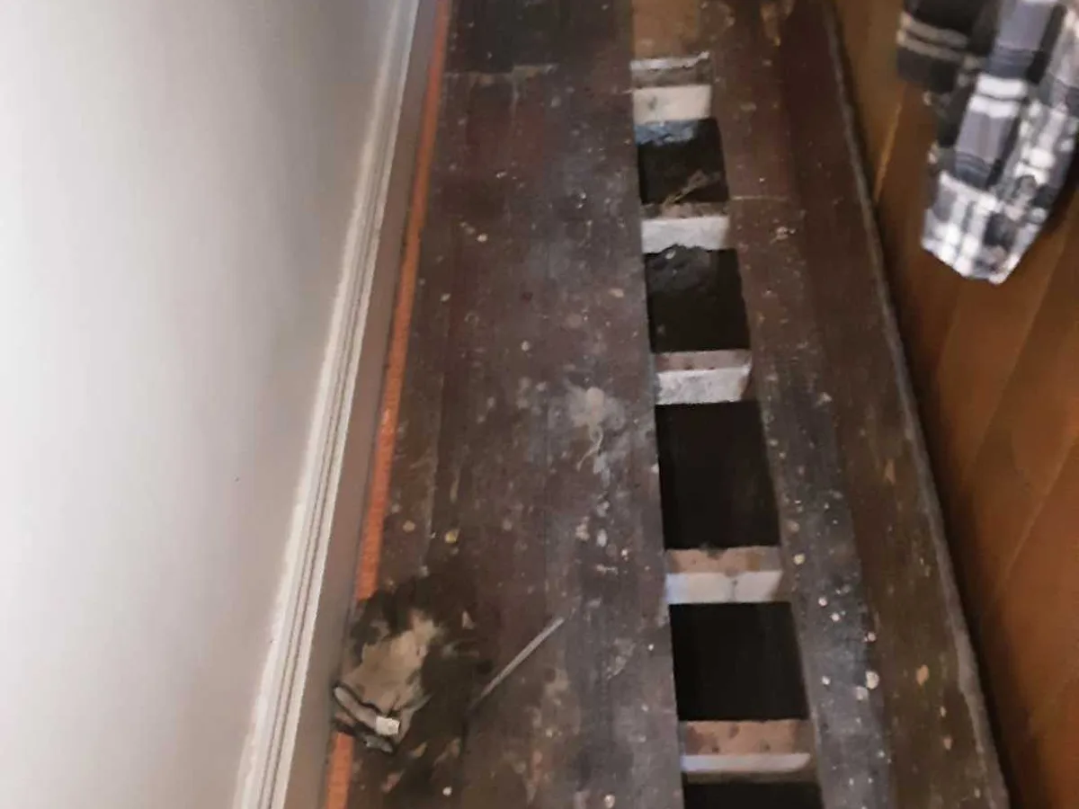 hallway floorboards lifted with multiple bays open during repair in progress to lead cold mains pipe