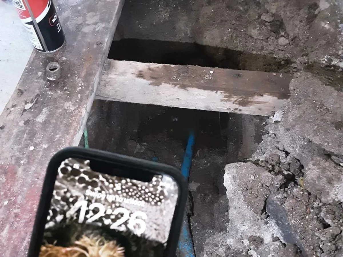 leak located at excavated sub-floor void beneath hallway floorboards showing wet ground