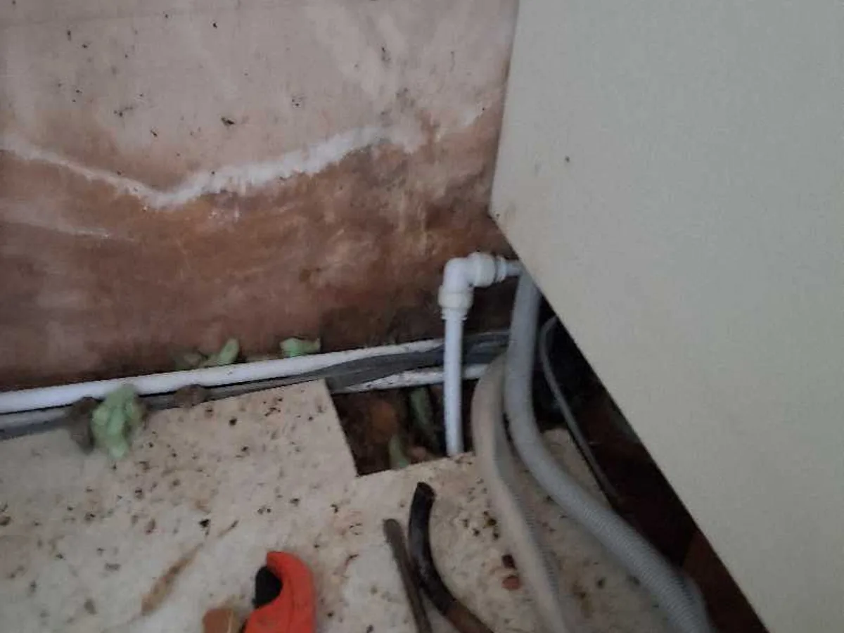 new push-fit pipe and elbow fitting installed as repair completed beneath kitchen wall