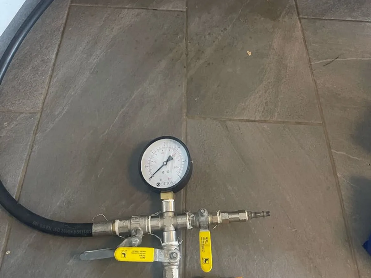 pressure gauge connected to cold water pipe under kitchen sink during leak detection