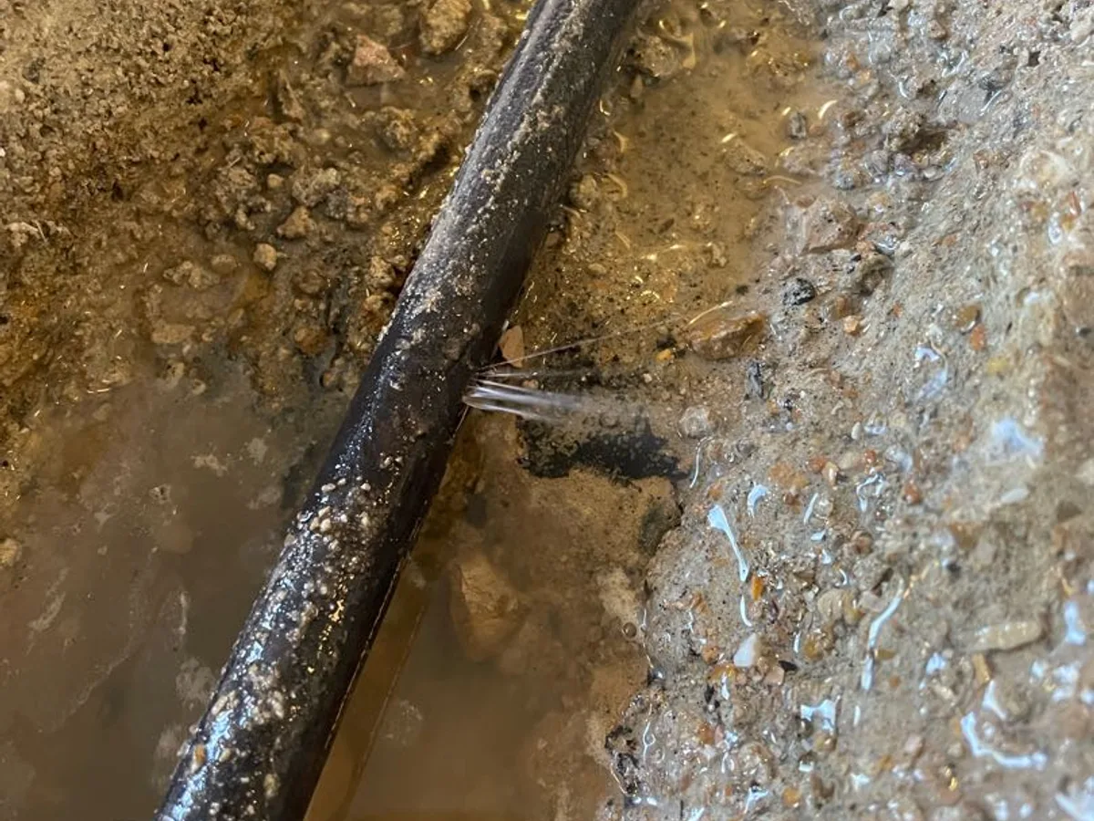 leak found at split in buried cold water pipe with water visibly escaping under concrete floor