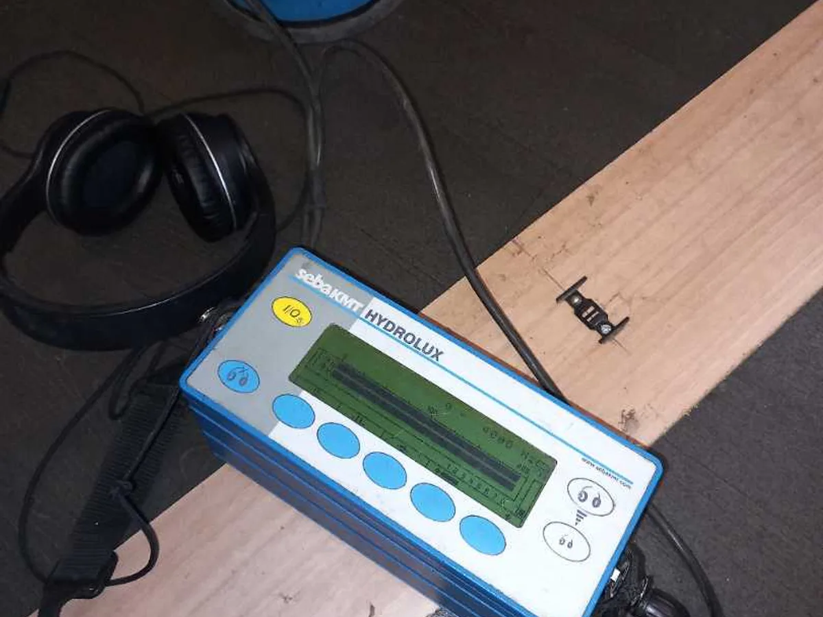 acoustic leak correlator unit with ground microphone on kitchen floor during leak detection