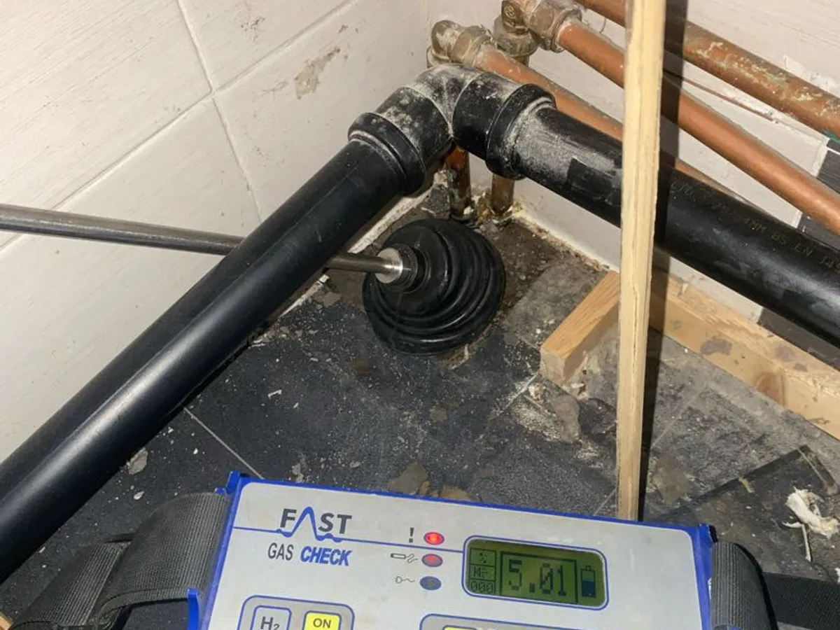 tracer gas detector probe at bathroom floor penetration during leak detection