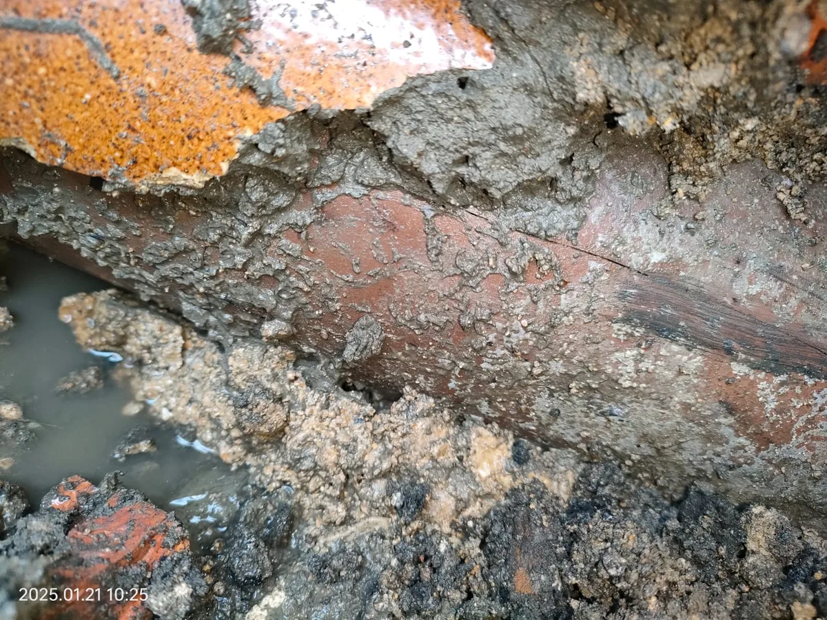 heavily corroded steel mains supply pipe exposed in waterlogged excavation during leak detection