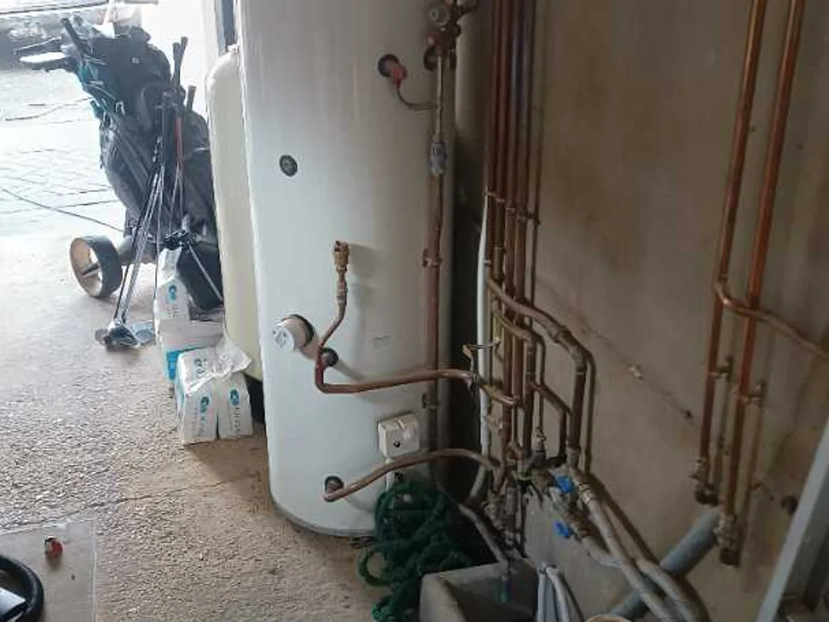 unvented hot water cylinder and copper pipework in garage at initial inspection before works started
