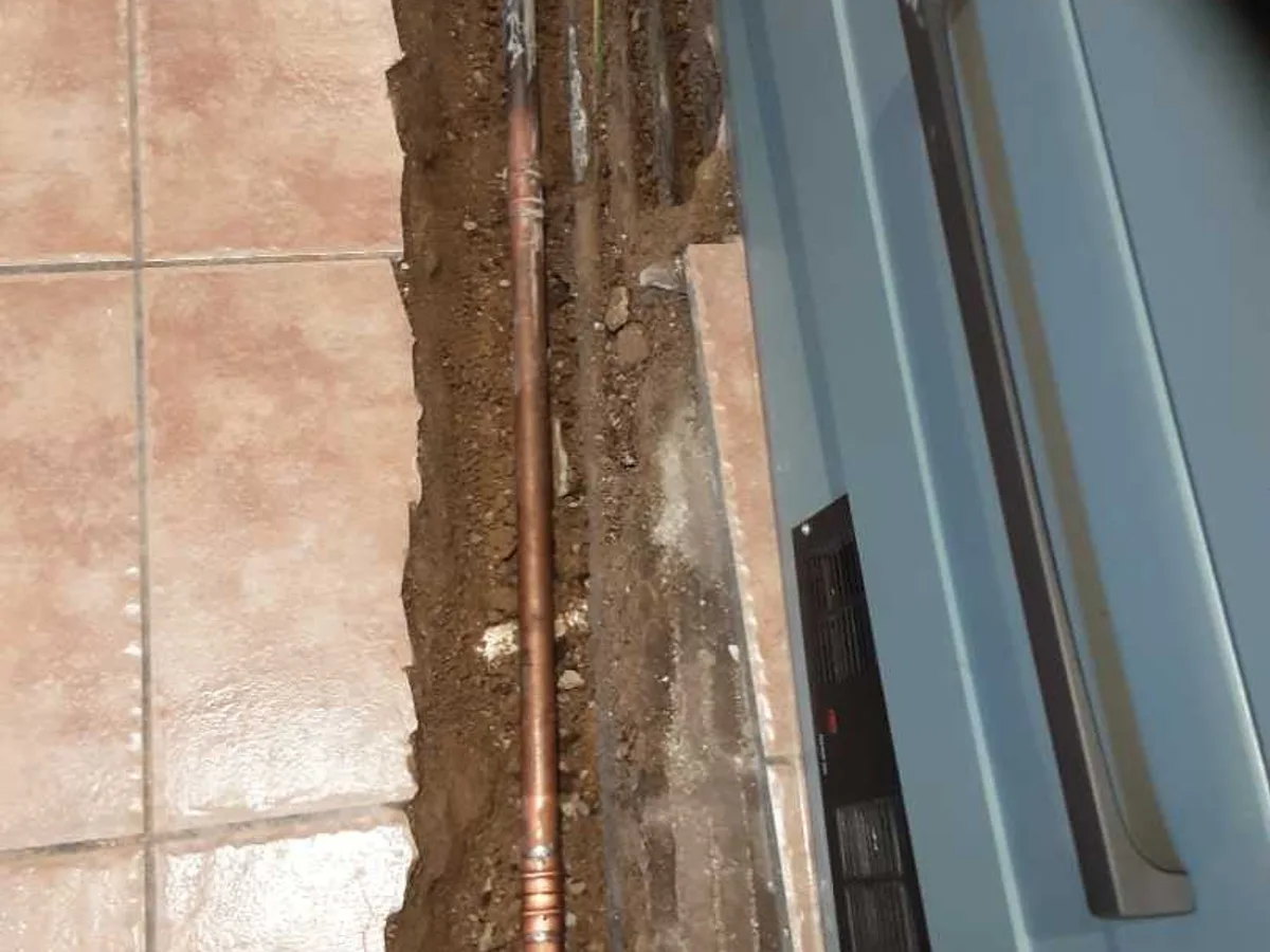 new section of 22mm copper pipe installed in floor trench as repair completed