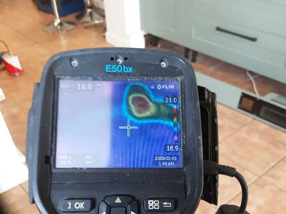 thermal imaging camera screen showing heat anomaly under kitchen floor during leak detection