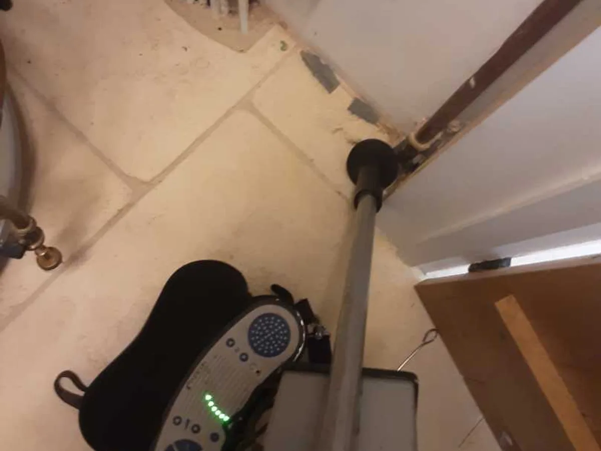acoustic listening probe on cupboard floor near pipework during leak detection