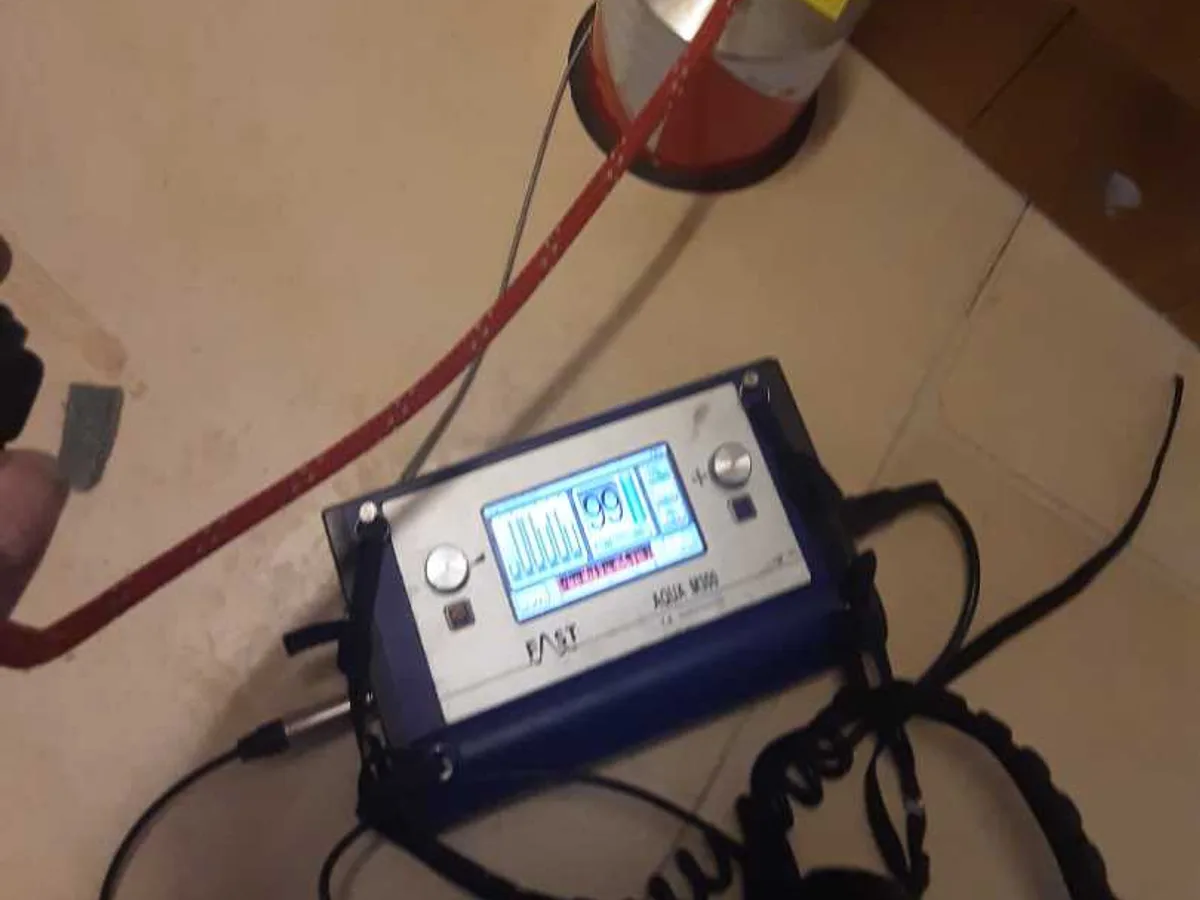 tracer gas detector unit with sensor placed on hallway tiled floor during leak detection