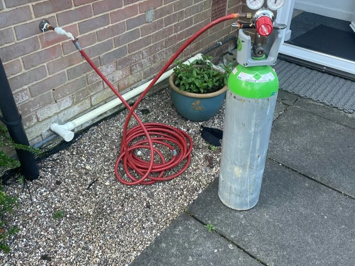 tracer gas cylinder connected to garden hose tap during leak detection