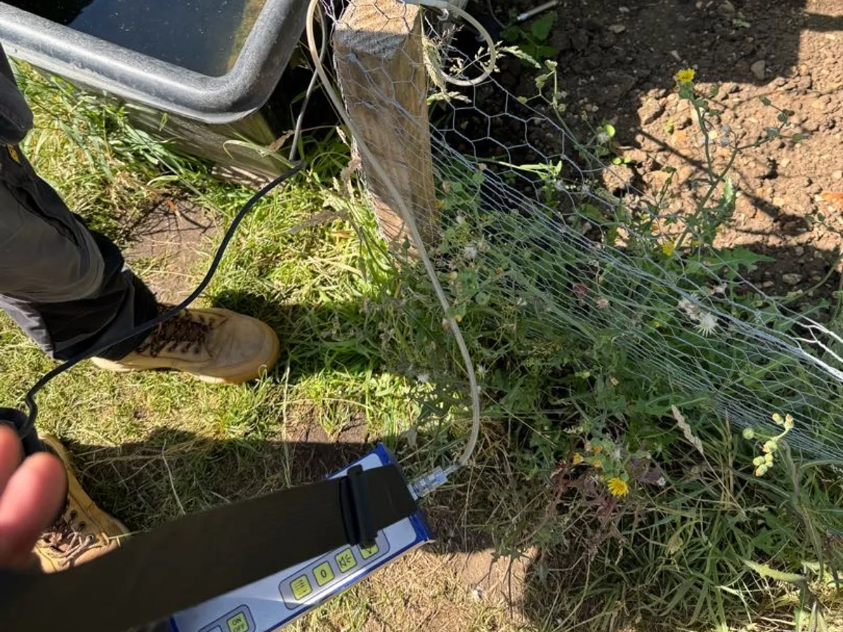tracer gas detector probe held near allotment standpipe fitting during leak detection survey