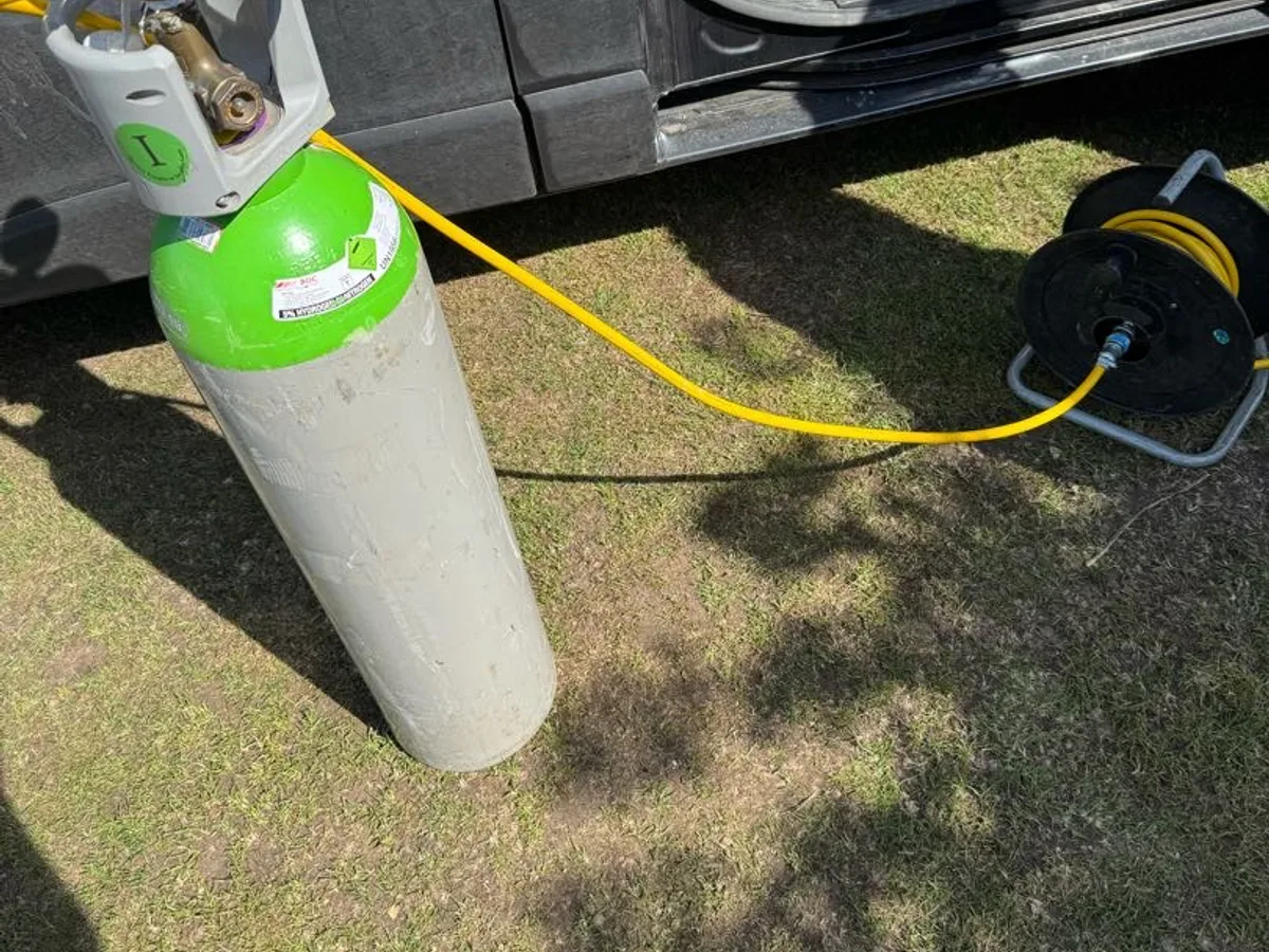 tracer gas cylinder connected via yellow hose to allotment standpipe during leak detection
