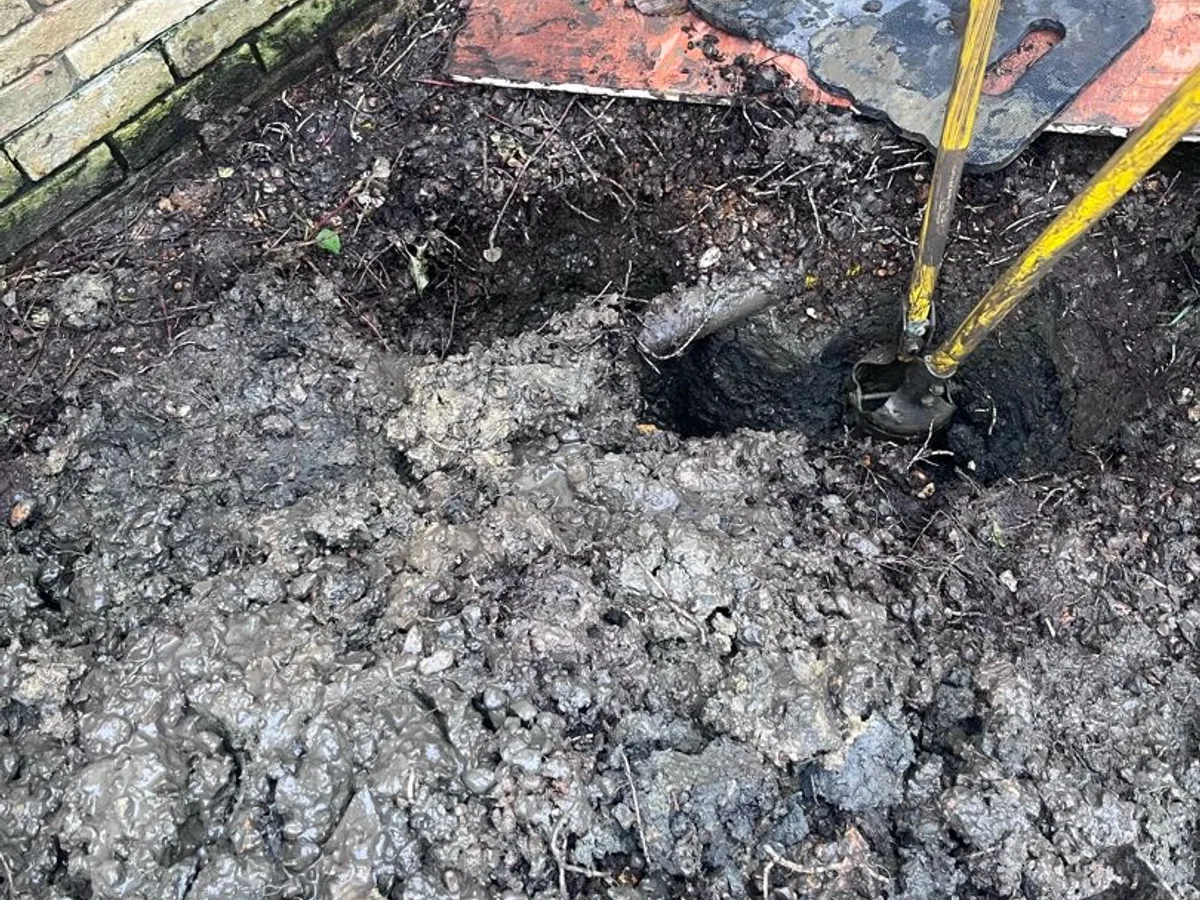 leak located at waterlogged excavation in front garden revealing saturated ground around mains pipework