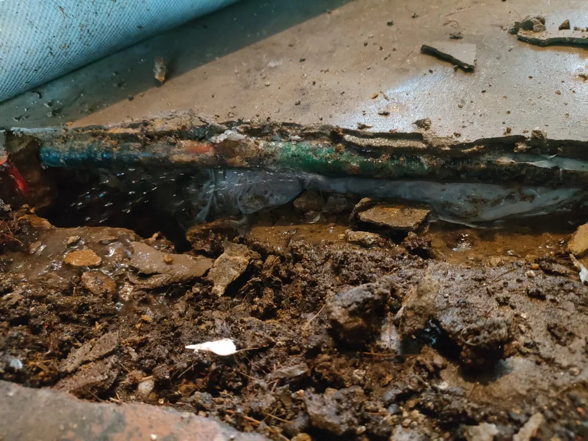 leak located at crushed and corroded copper mains pipe exposed beneath concrete floor