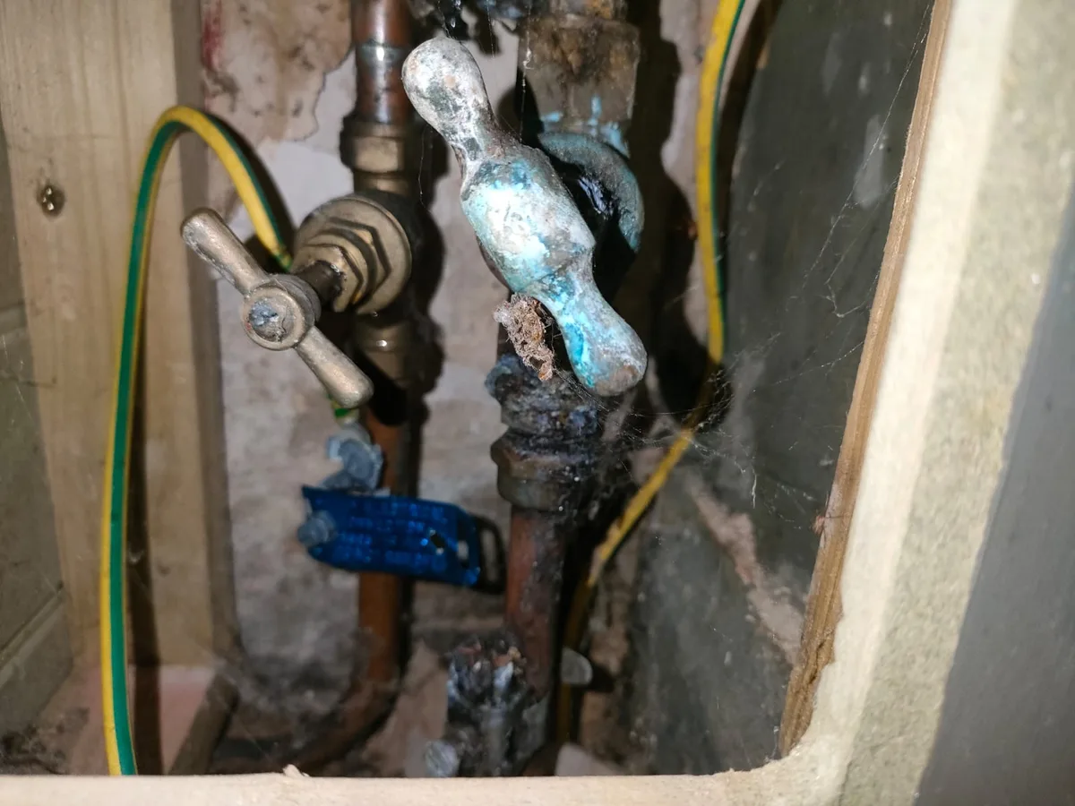 corroded internal stopcock with condensation in access panel during leak detection