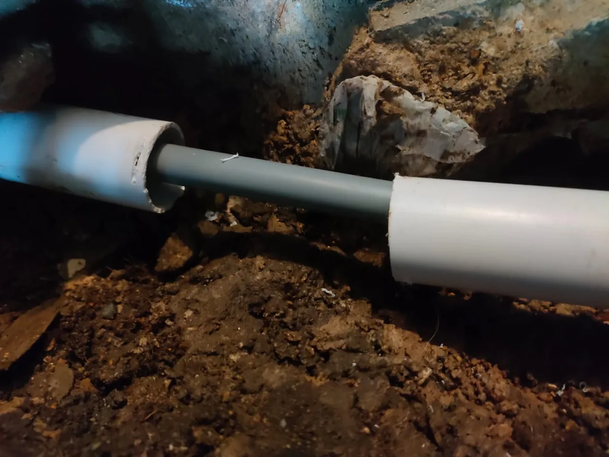 repaired mains pipe sleeved in plastic ducting repair completed beneath pub floor