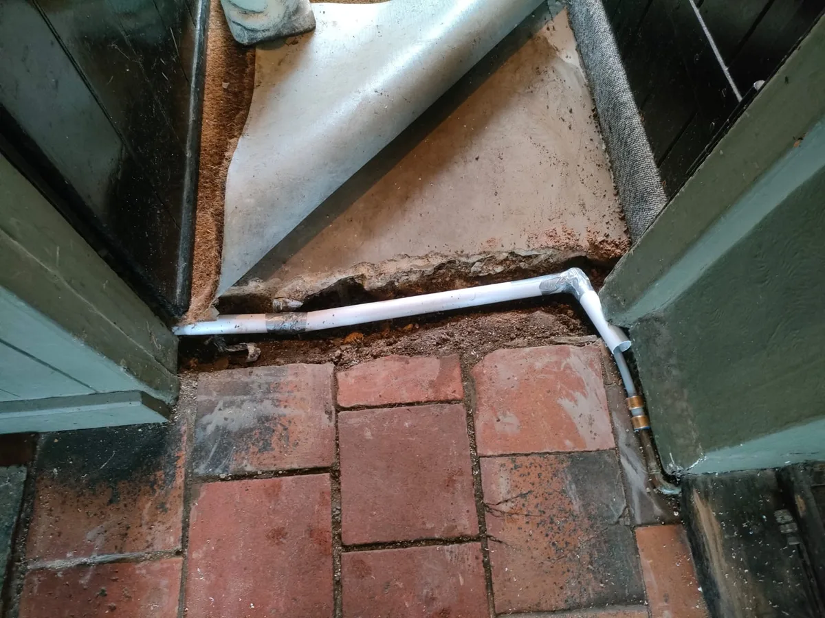 sleeved replacement pipe laid across door threshold area reinstated after repair