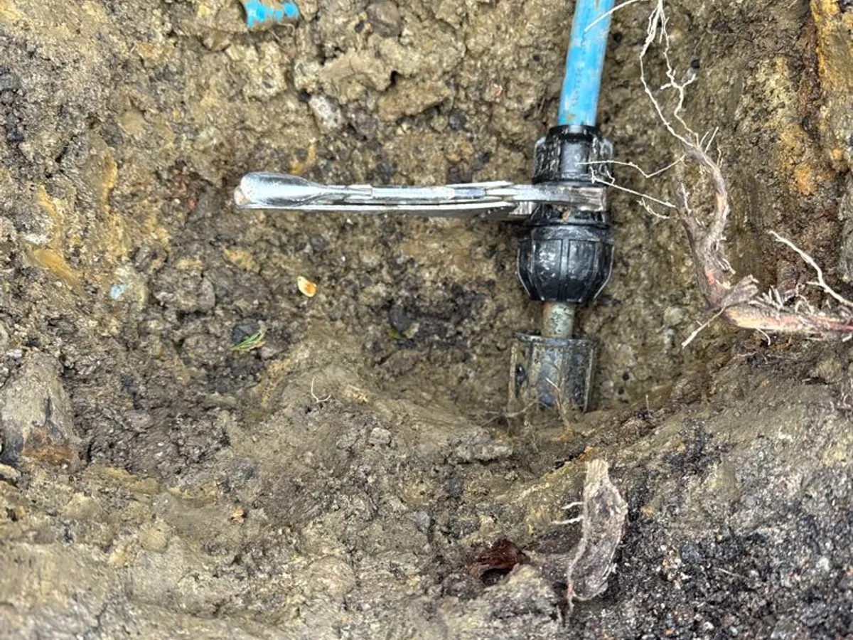 replacement transitional coupling fitted to mains supply pipe in excavation as repair completed