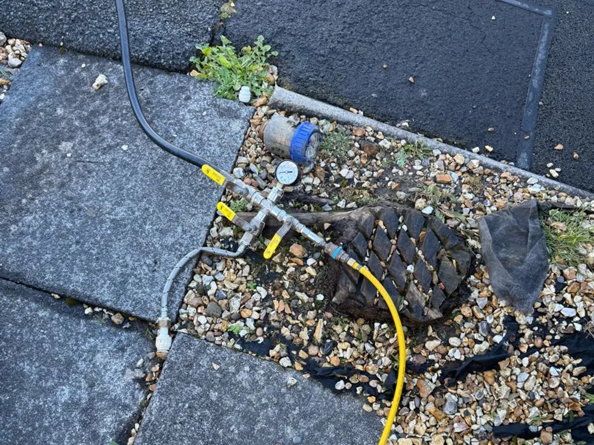 tracer gas hose and pressure manifold connected at water meter box during leak detection