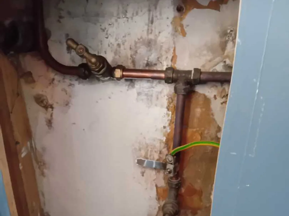 leak found at obsolete internal stopvalve exposed behind kitchen boxing with corroded pipework