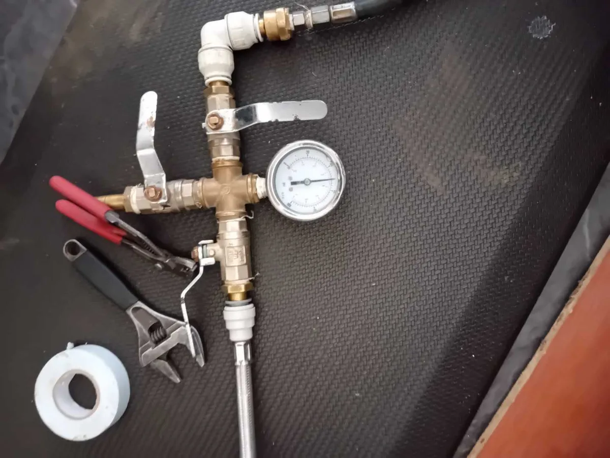 pressure test manifold with gauge and spanners laid out during leak detection investigation
