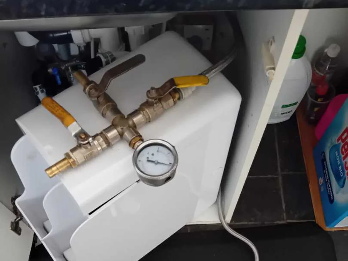 tracer gas injection unit with pressure gauge connected under kitchen sink during leak detection