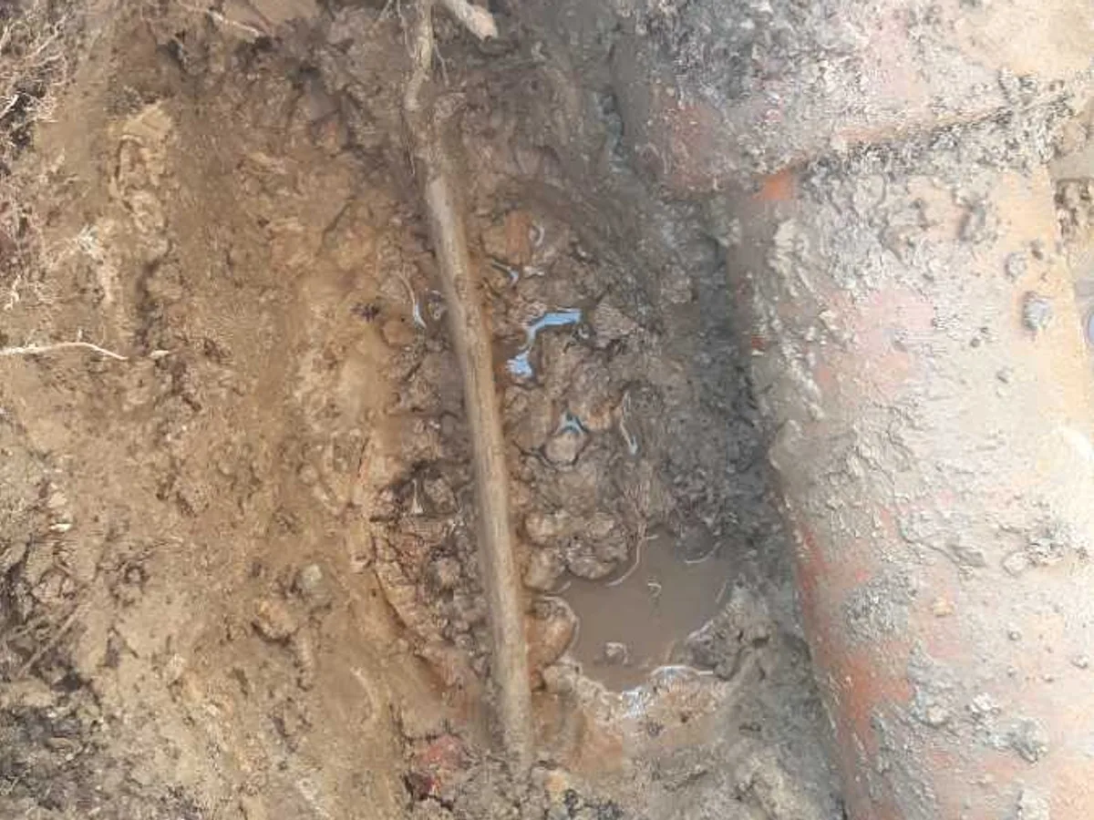 leak located at damaged copper mains pipe exposed in excavation beneath concrete pathway
