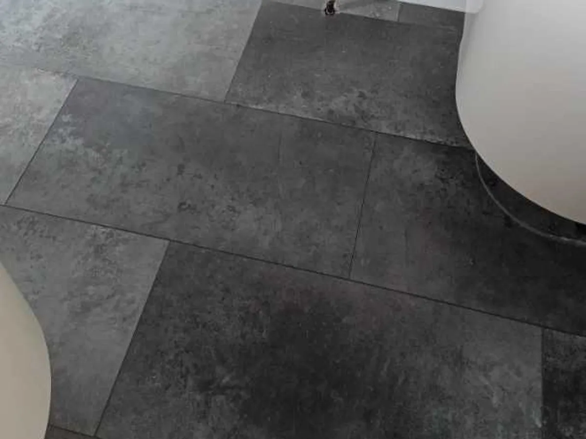damp patch on bathroom floor tiles near towel rail before leak detection works