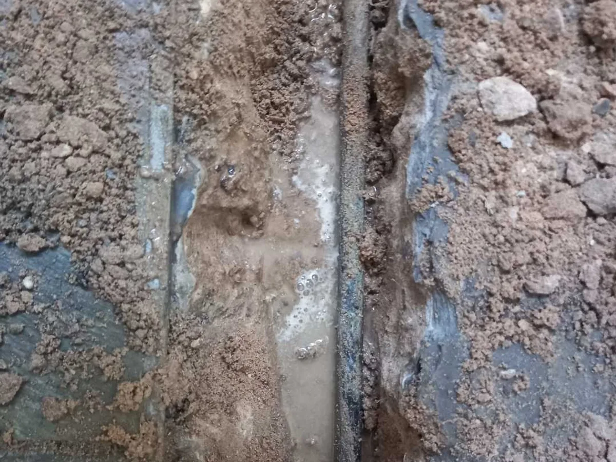 fault exposed at damaged 15mm copper tube in wet subfloor with water visible