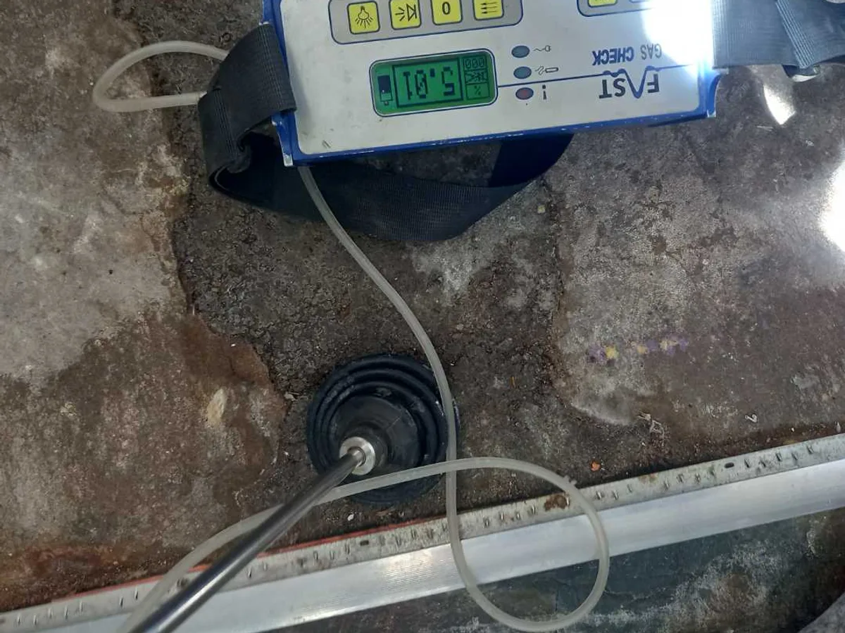 tracer gas detector probe inserted into hallway floor during leak detection survey
