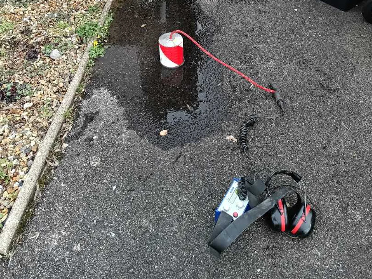 acoustic listening device and headphones on wet tarmac driveway during leak detection