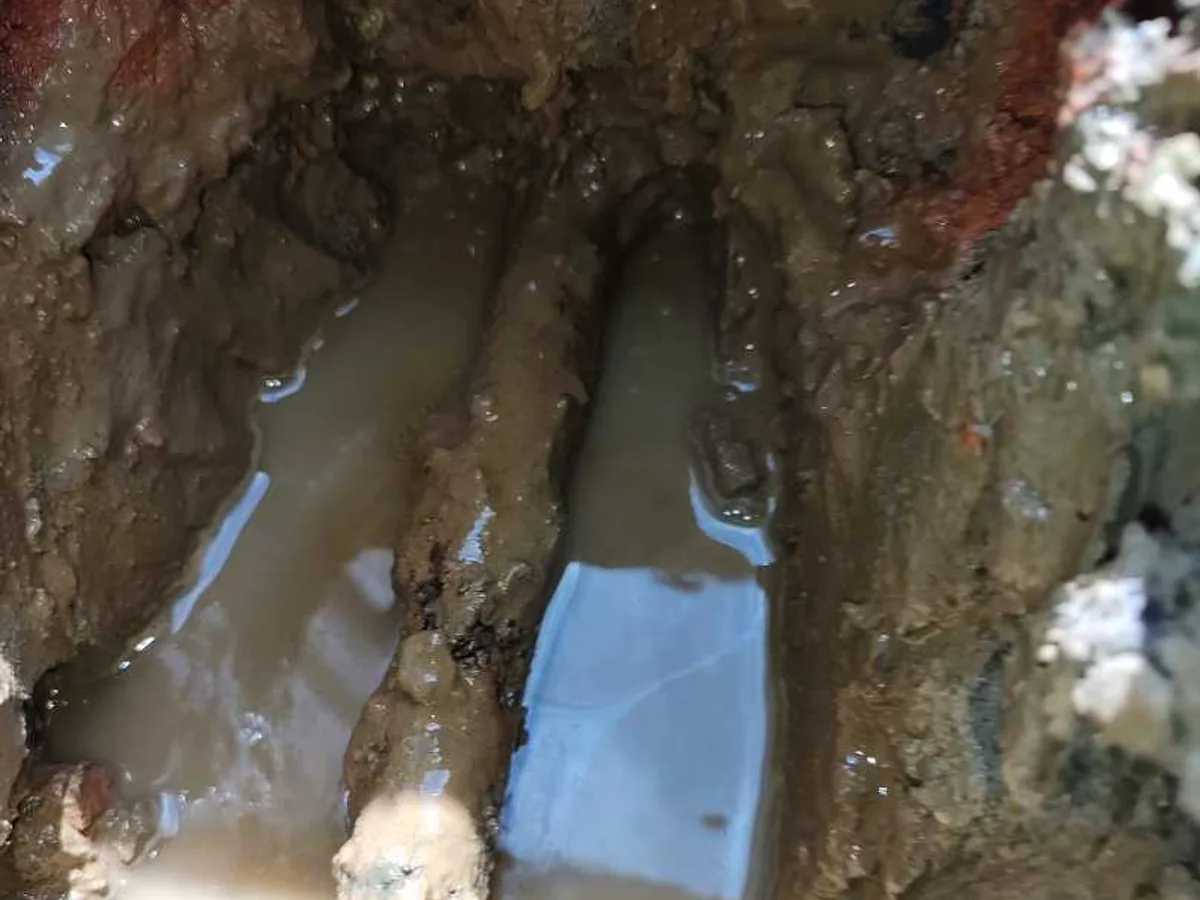 leak found at corroded steel mains pipework standing in water-filled trench beneath hallway