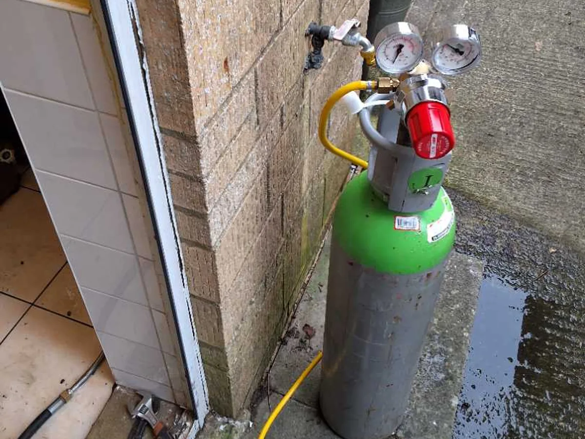 tracer gas cylinder connected at external utility room pipe entry during leak detection