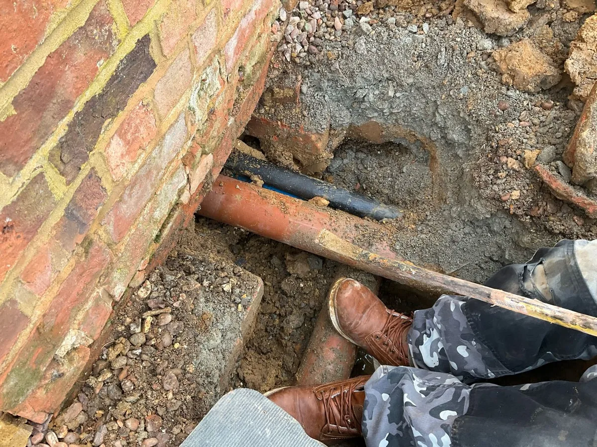 leak located at blue MDPE water mains pipe beneath exterior back kitchen wall during excavation