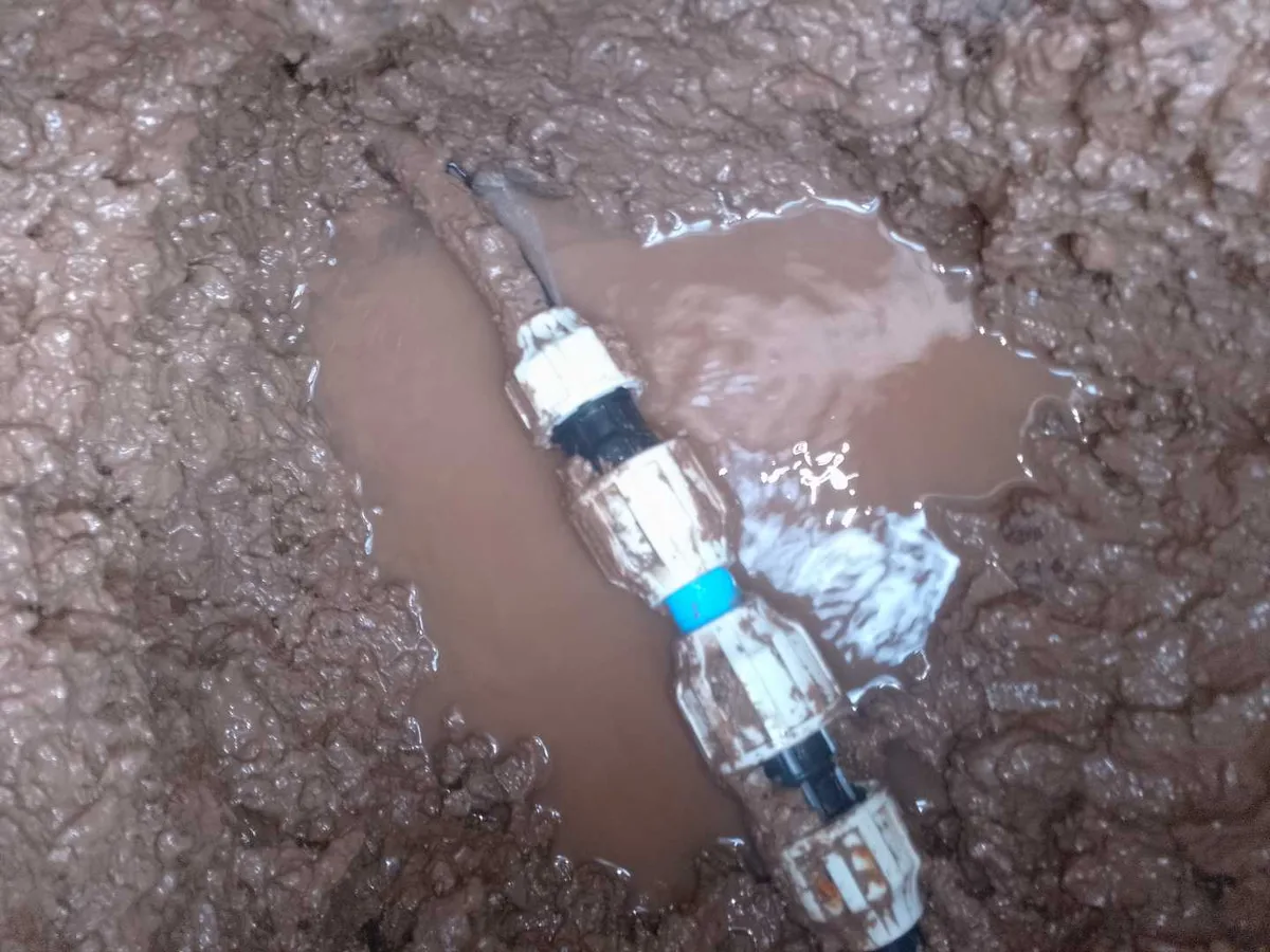 leak located at failed underground transfer couplers surrounded by muddy water in excavation
