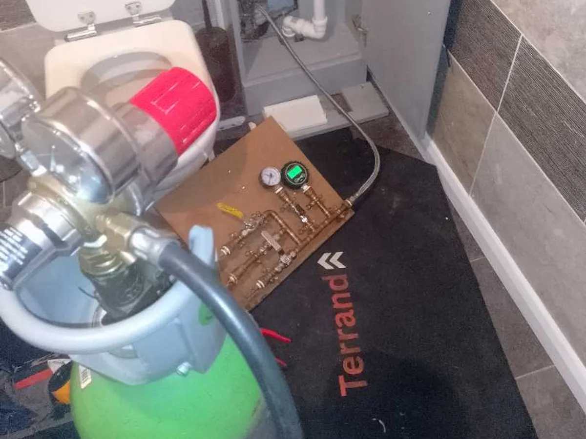 tracer gas cylinder and pressure testing manifold in use during leak detection investigation in bathroom