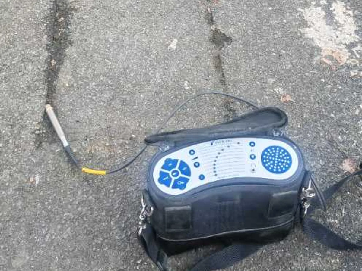 specialist gas analyser placed on tarmac repair patch during leak detection survey of driveway