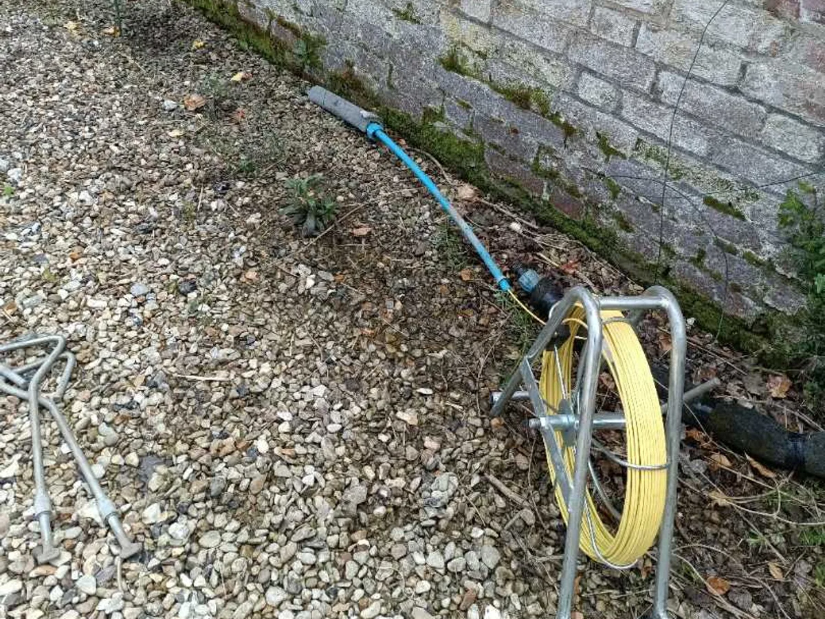 pipe-tracing rod and cable reel laid along gravel path during leak detection