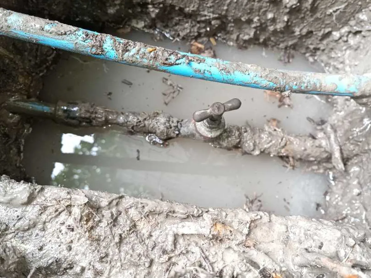 leak located at buried stop valve on blue MDPE pipe in waterlogged excavation