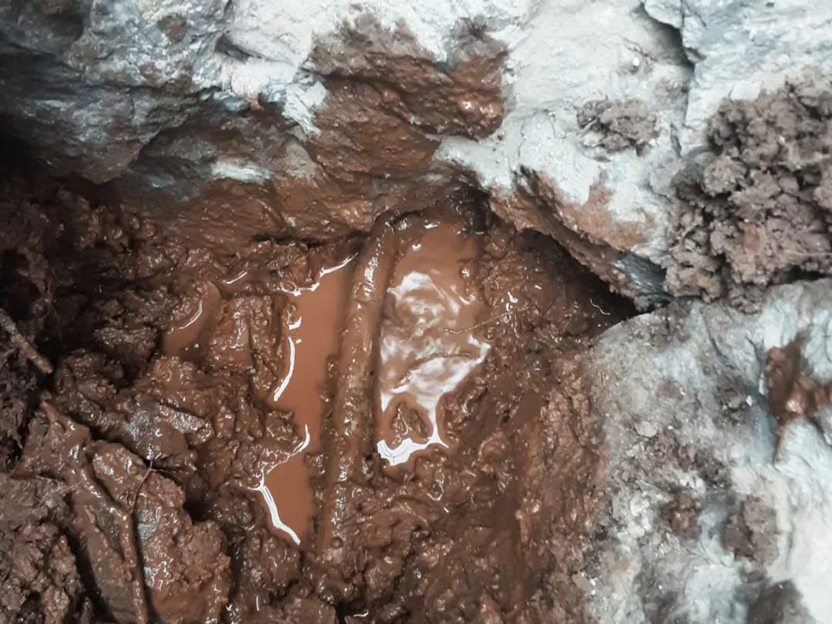 leak located at damaged lead mains supply with waterlogged soil in excavation near boundary wall