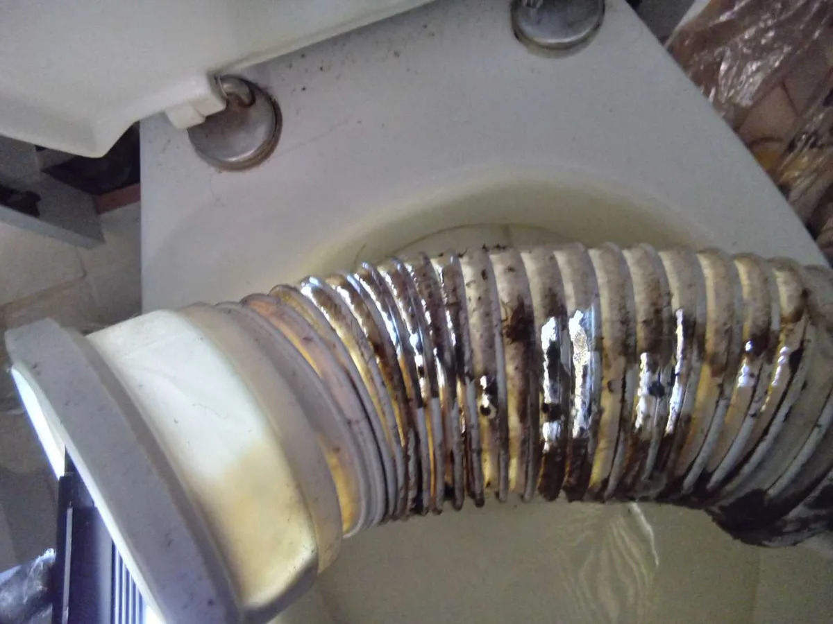 fault exposed at corroded flexible toilet pan connector with multiple holes beneath cistern